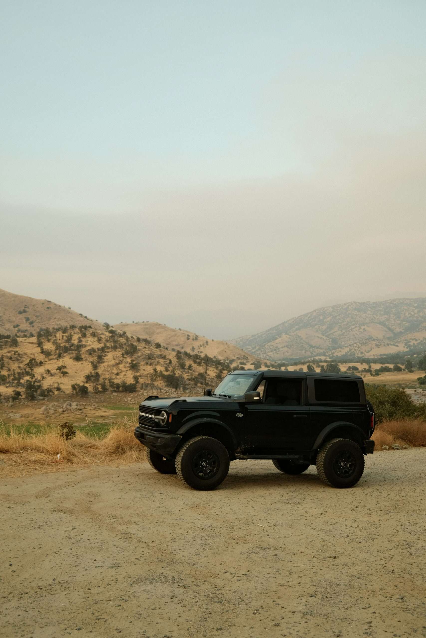 A black jeep is parked on a dirt road